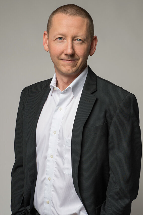 Relaxed executive portrait of a man in a charcoal blazer