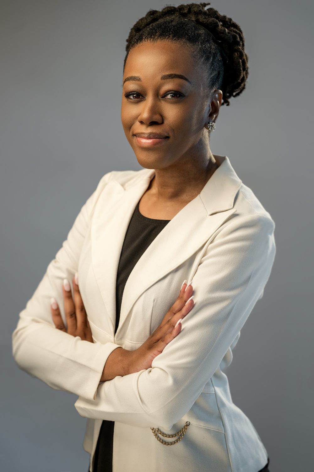 Executive in a white blazer with arms crossed on a gray background