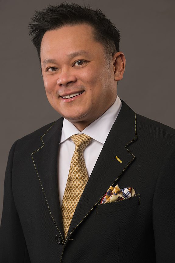 Executive headshot of a man in a light gray suit and blue tie