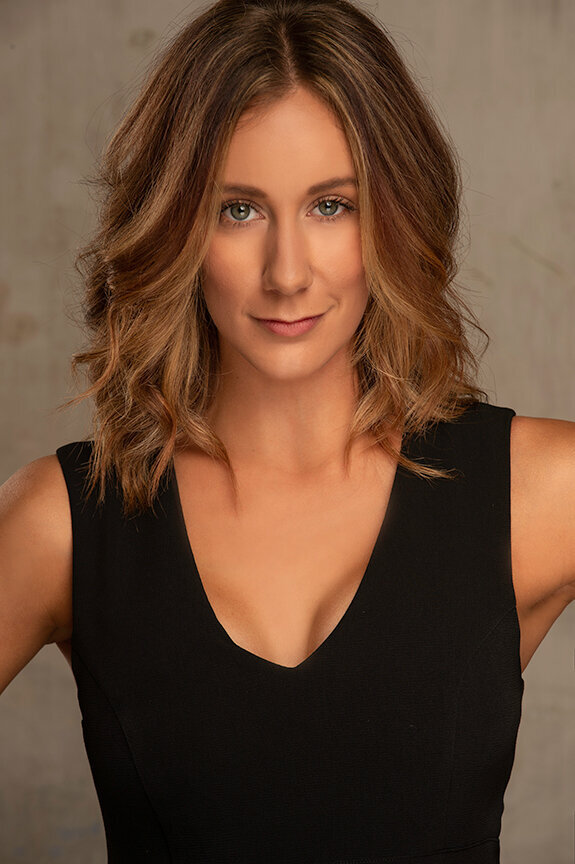 Executive headshot of a woman in a black dress against a warm neutral background